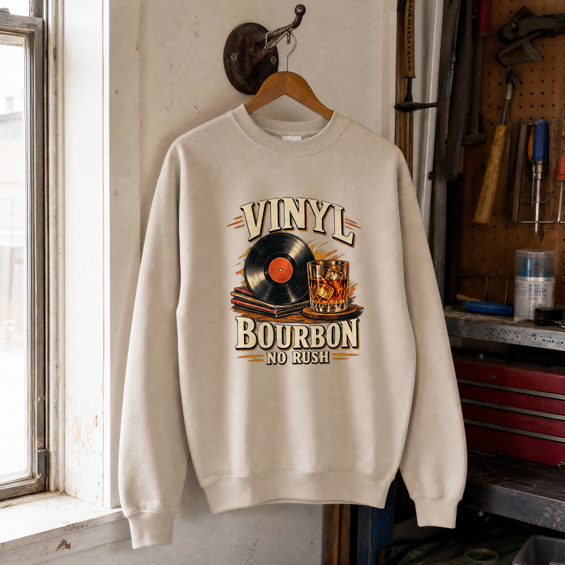 Cream vintage sweatshirt hanging with printed Vinyl Bourbon No Rush record and bourbon design.