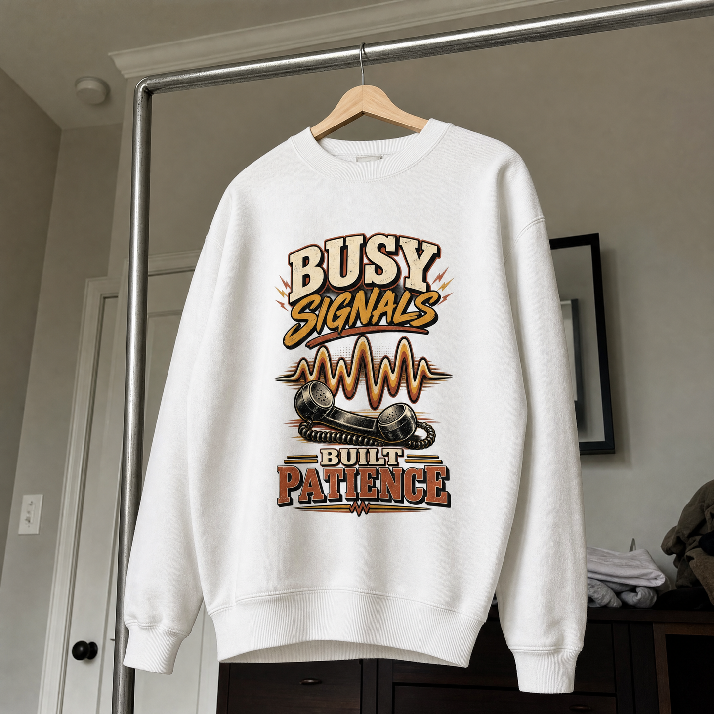 White vintage sweatshirt hanging with Busy Signals Built Patience printed design.