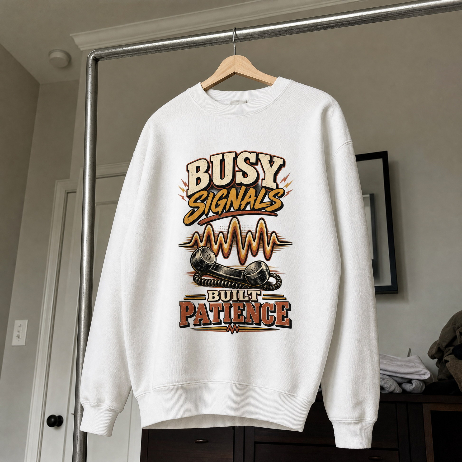 White vintage sweatshirt hanging with Busy Signals Built Patience printed design.