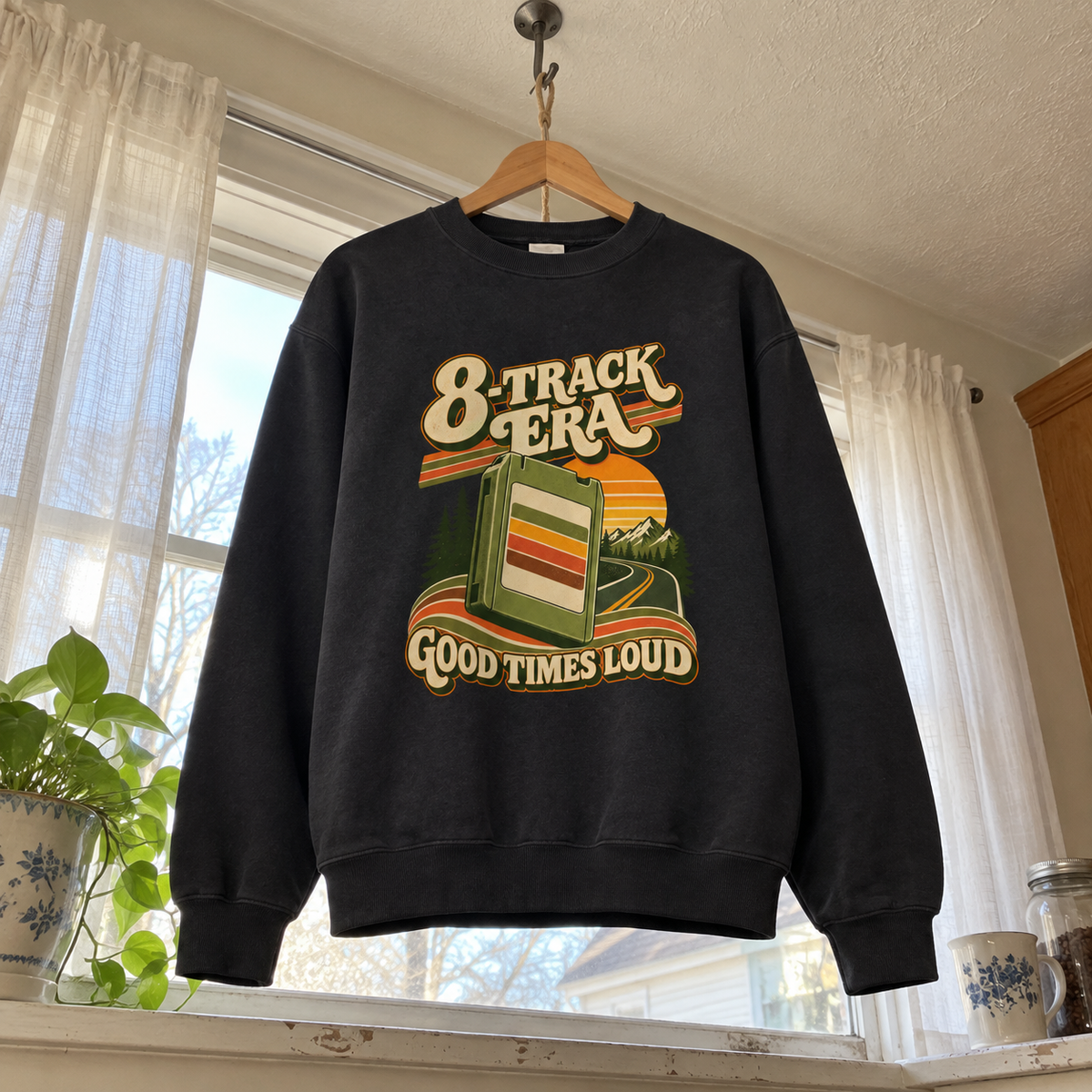 Black vintage sweatshirt hanging by window with printed 8-Track Era Good Times Loud design.