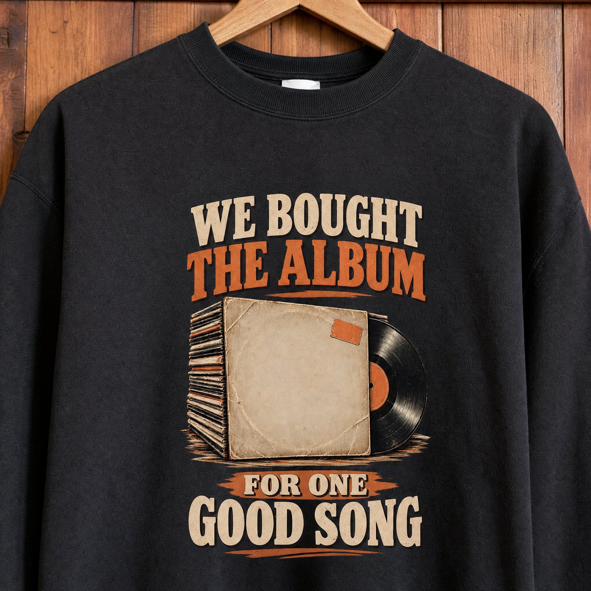 Black vintage sweatshirt hanging on wooden wall, printed with album slogan about one good song
