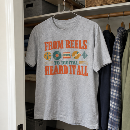 Gray vintage t-shirt hanging with printed From Reels To Digital Heard It All slogan design