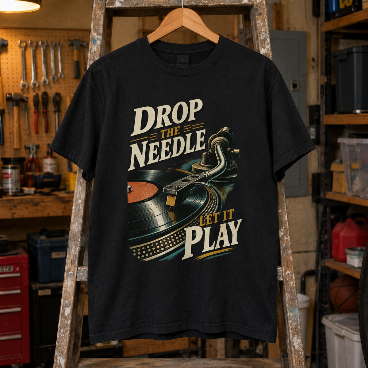 Black vintage t-shirt hanging with printed Drop The Needle. Let It Play turntable design.