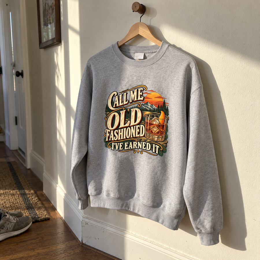 Gray vintage sweatshirt hanging with printed “Call Me Old Fashioned. I’ve Earned It” slogan