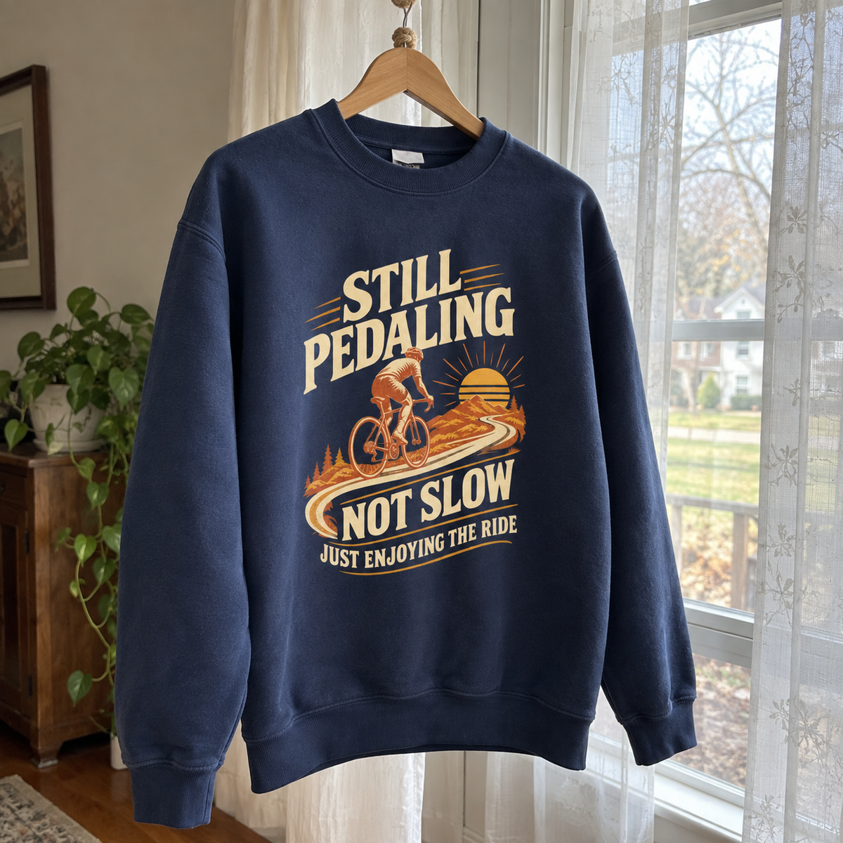 Navy vintage sweatshirt hanging on wooden hanger with cyclist and printed ride slogan