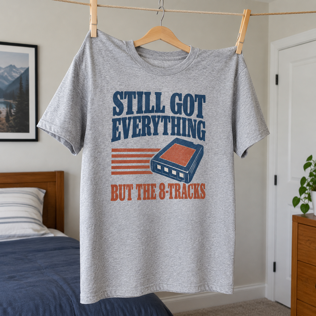 Gray vintage t-shirt hanging with printed Still Got Everything But The 8-Tracks slogan and cassette design