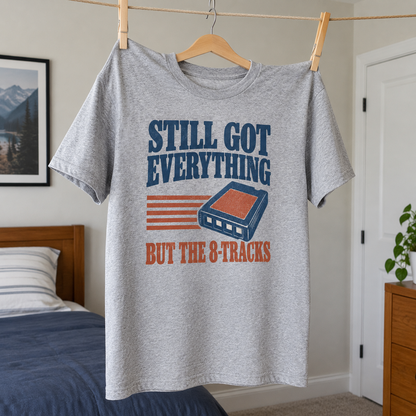 Gray vintage t-shirt hanging with printed Still Got Everything But The 8-Tracks slogan and cassette design