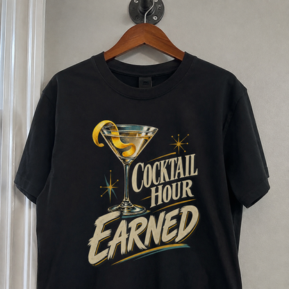 Black vintage t-shirt hanging on a wooden hanger with printed Cocktail Hour Earned cocktail graphic