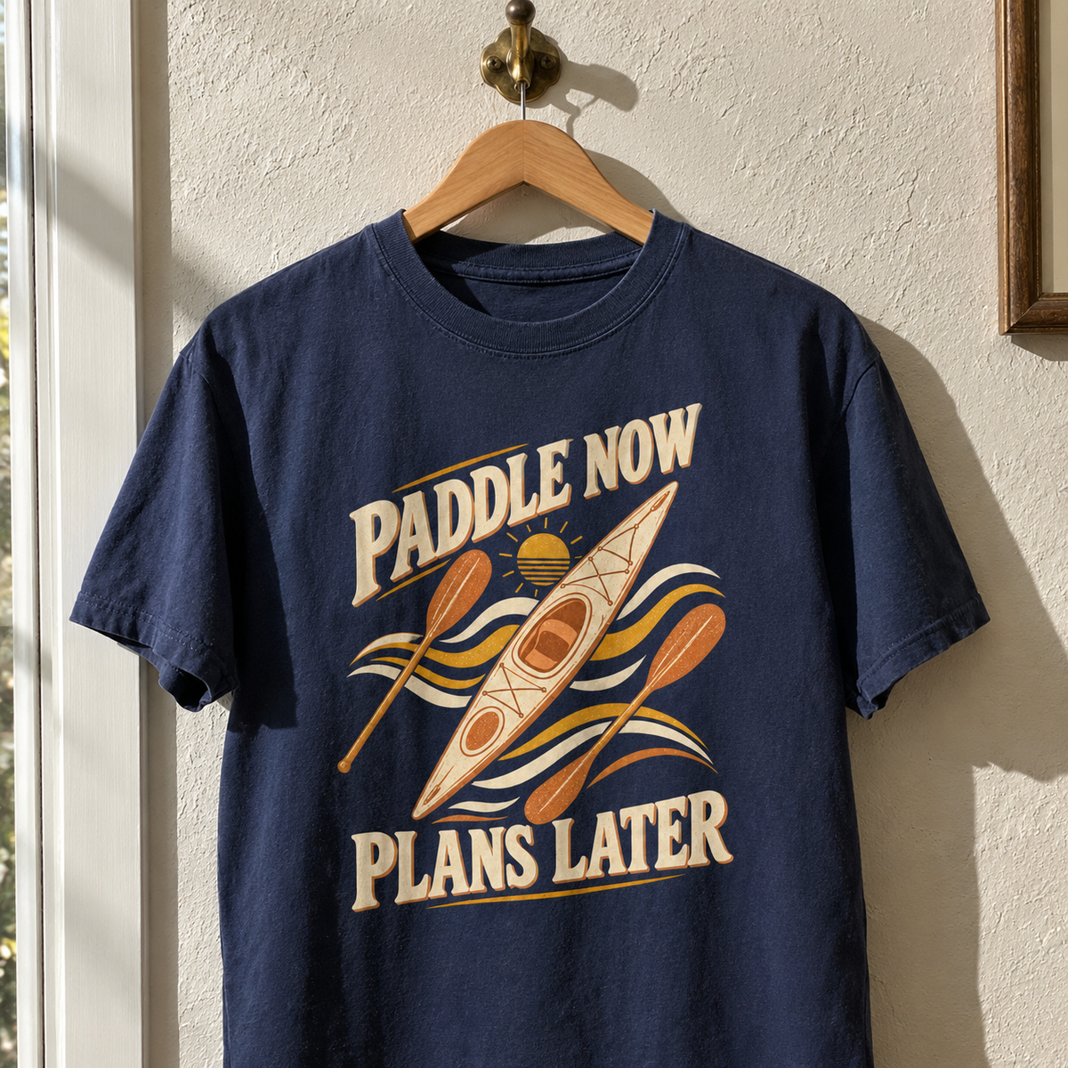 Navy vintage t-shirt hanging with printed kayak, paddles, and “Paddle Now. Plans Later” slogan