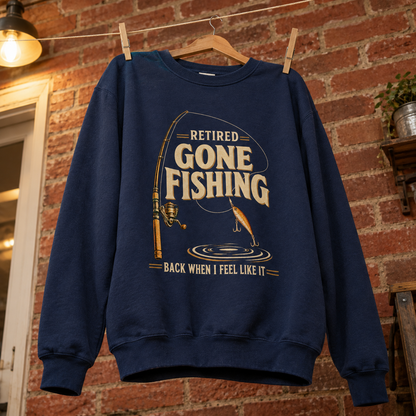 Navy vintage sweatshirt hanging with printed Retired Gone Fishing slogan and fishing rod graphic against brick wall
