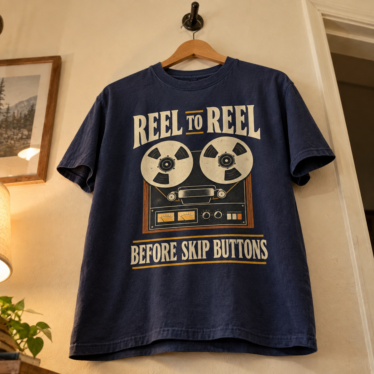 Navy vintage t-shirt with printed reel-to-reel graphic and Before Skip Buttons slogan, hanging.