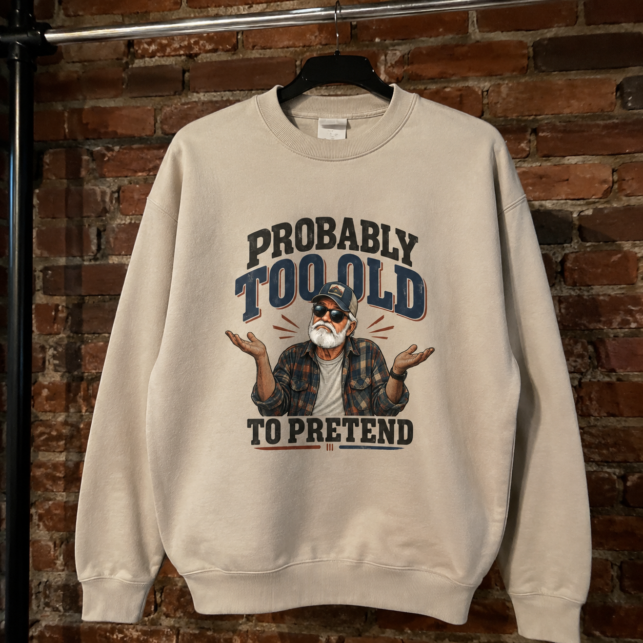 Cream vintage sweatshirt hanging with printed Probably Too Old To Pretend senior man shrugging design