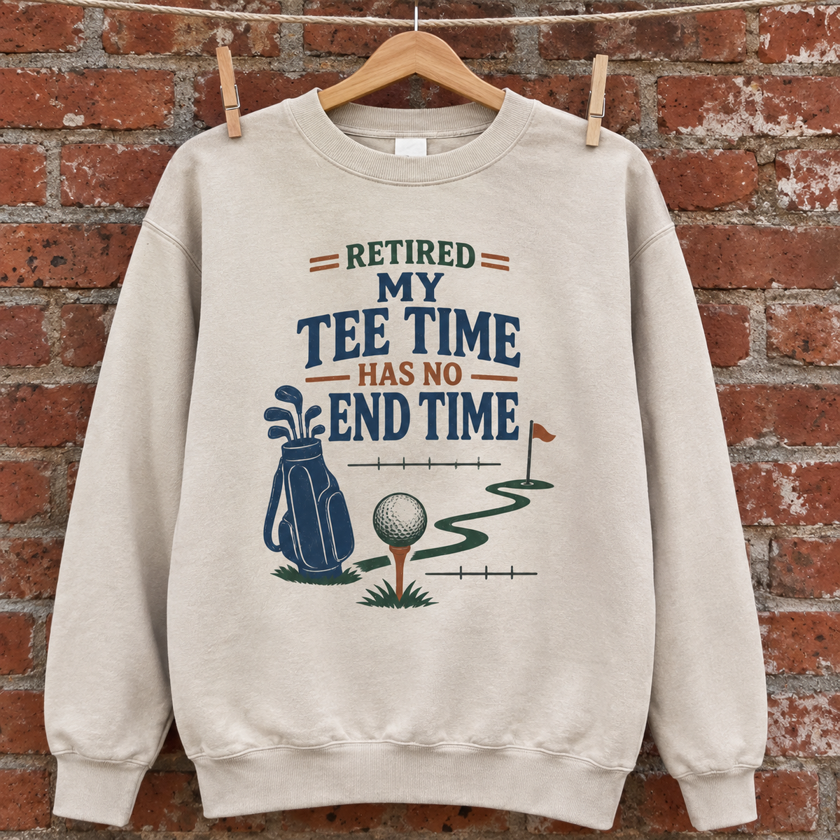Cream vintage sweatshirt with printed golf slogan, hanging against a brick wall.