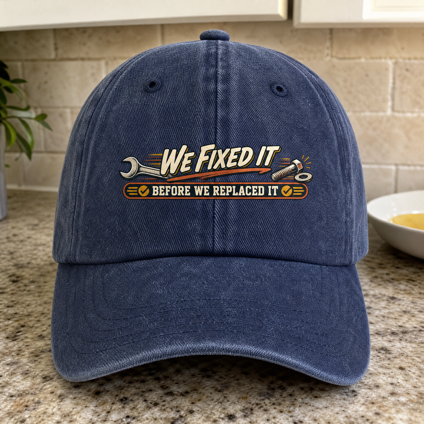 Navy vintage washed cap with printed “We Fixed It Before We Replaced It” slogan, front-facing.