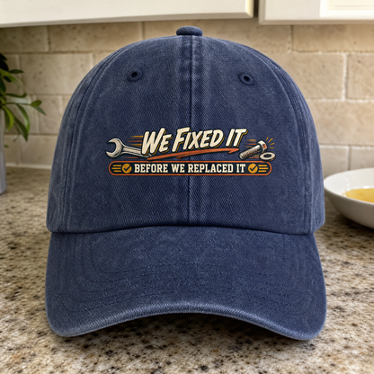 Navy vintage washed cap with printed “We Fixed It Before We Replaced It” slogan, front-facing.