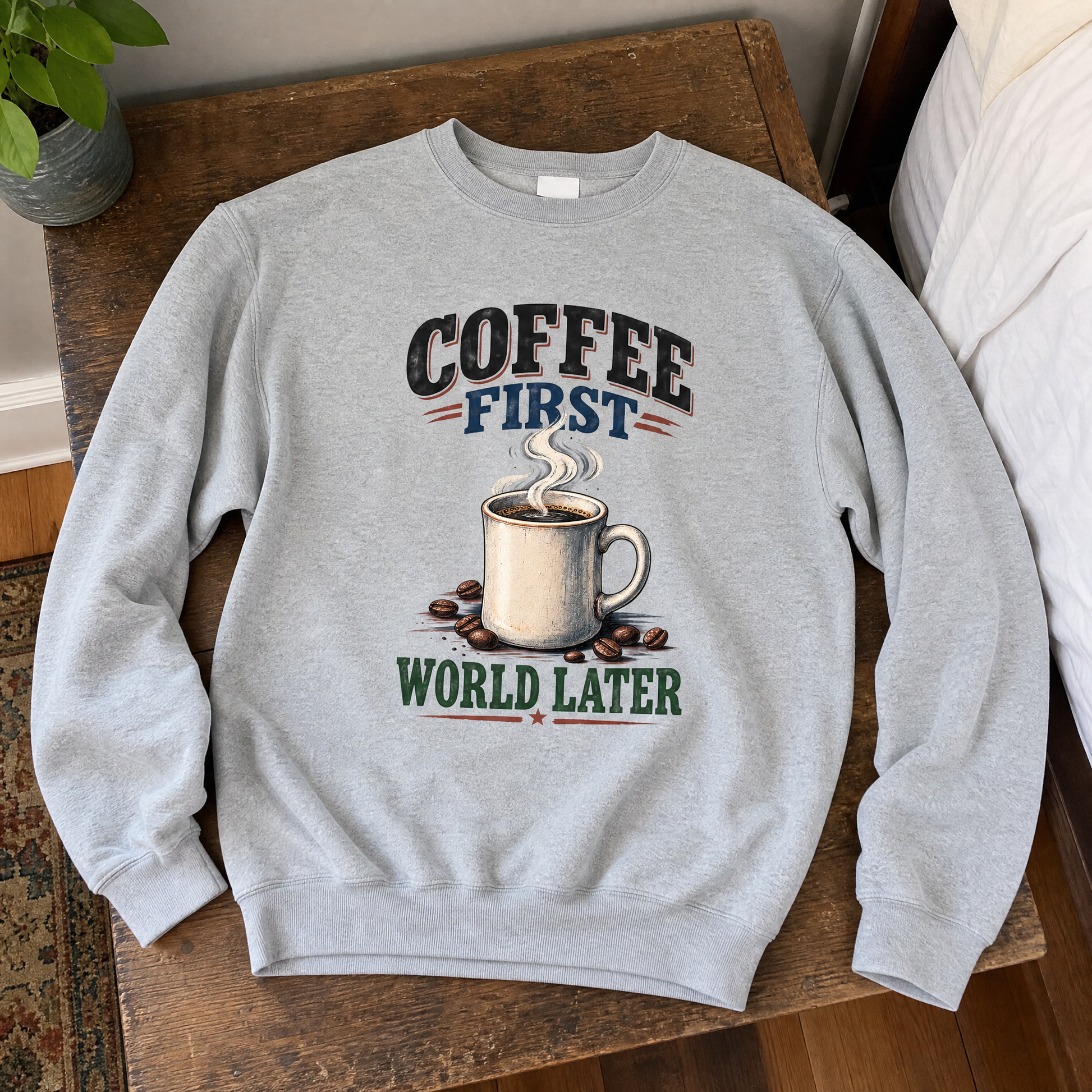 Light gray vintage sweatshirt with printed “Coffee First. World Later” coffee cup design, top view