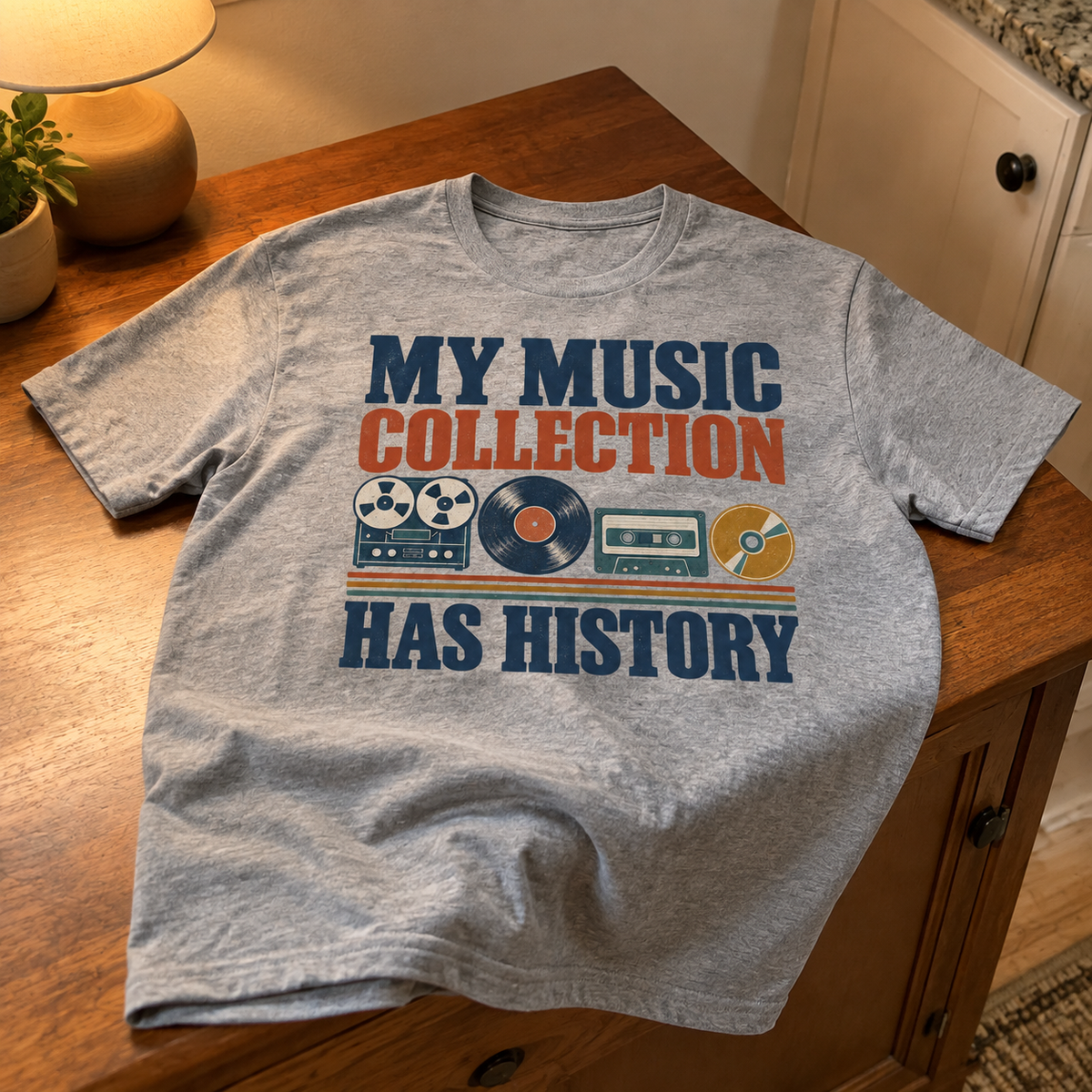 Gray vintage t-shirt printed with “My Music Collection Has History” and retro music graphics, overhead view