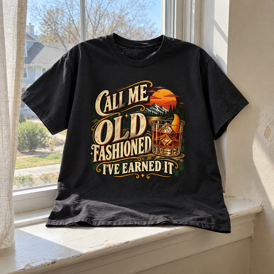Black vintage t-shirt with printed “Call Me Old Fashioned. I’ve Earned It” slogan on windowsill.