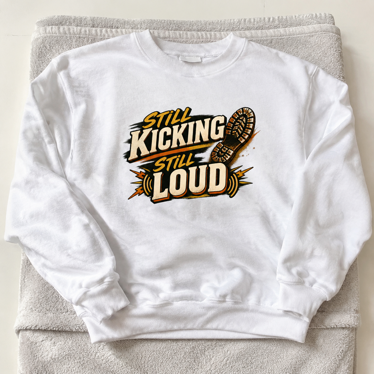 White vintage sweatshirt with printed Still Kicking Still Loud slogan design flat lay view