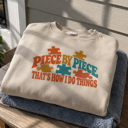 Cream vintage sweatshirt with colorful puzzle pieces and “Piece By Piece” printed design, hero view