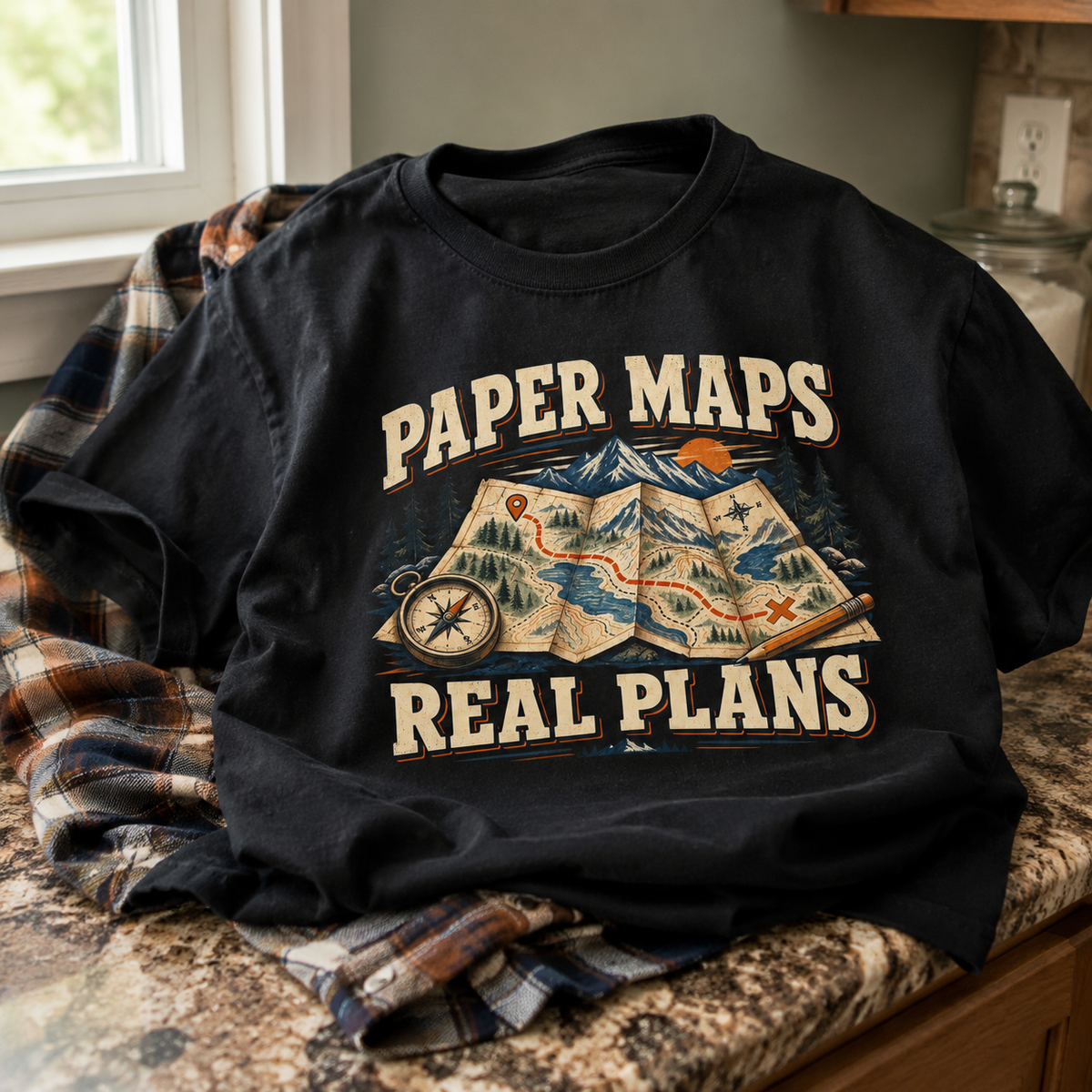 Black vintage t-shirt printed with Paper Maps Real Plans design on rustic indoor setting