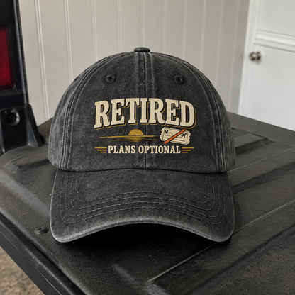 Black vintage washed cap with printed “Retired Plans Optional” slogan and travel graphic.