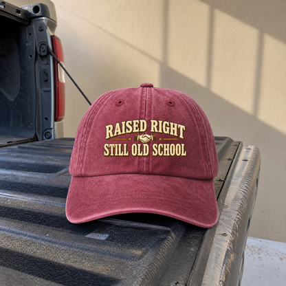 Burgundy vintage washed cap printed with Raised Right Still Old School slogan front view