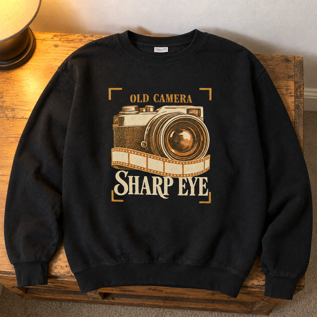 Black vintage sweatshirt with printed Old Camera Sharp Eye design, overhead hero view.
