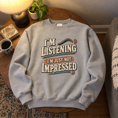 Gray vintage sweatshirt with I'm Listening I'm Just Not Impressed print on wooden table