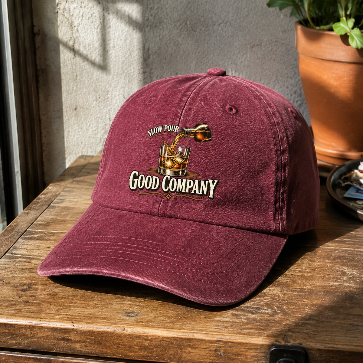 Maroon vintage washed cap with printed Slow Pour Good Company slogan on wooden surface