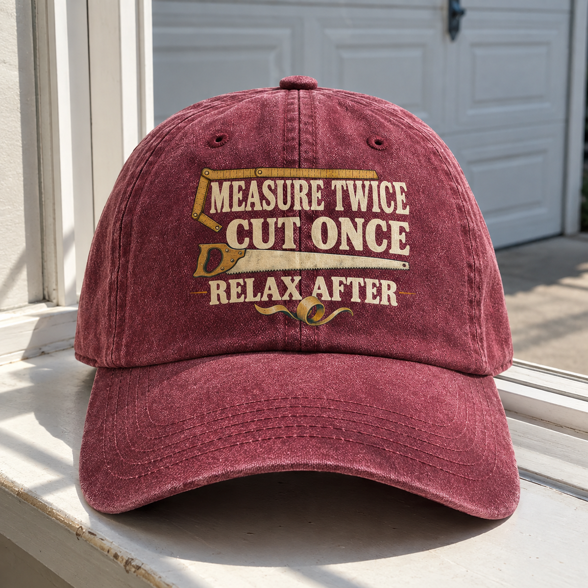 Burgundy vintage washed cap with printed “Measure Twice Cut Once. Relax After” slogan, front view