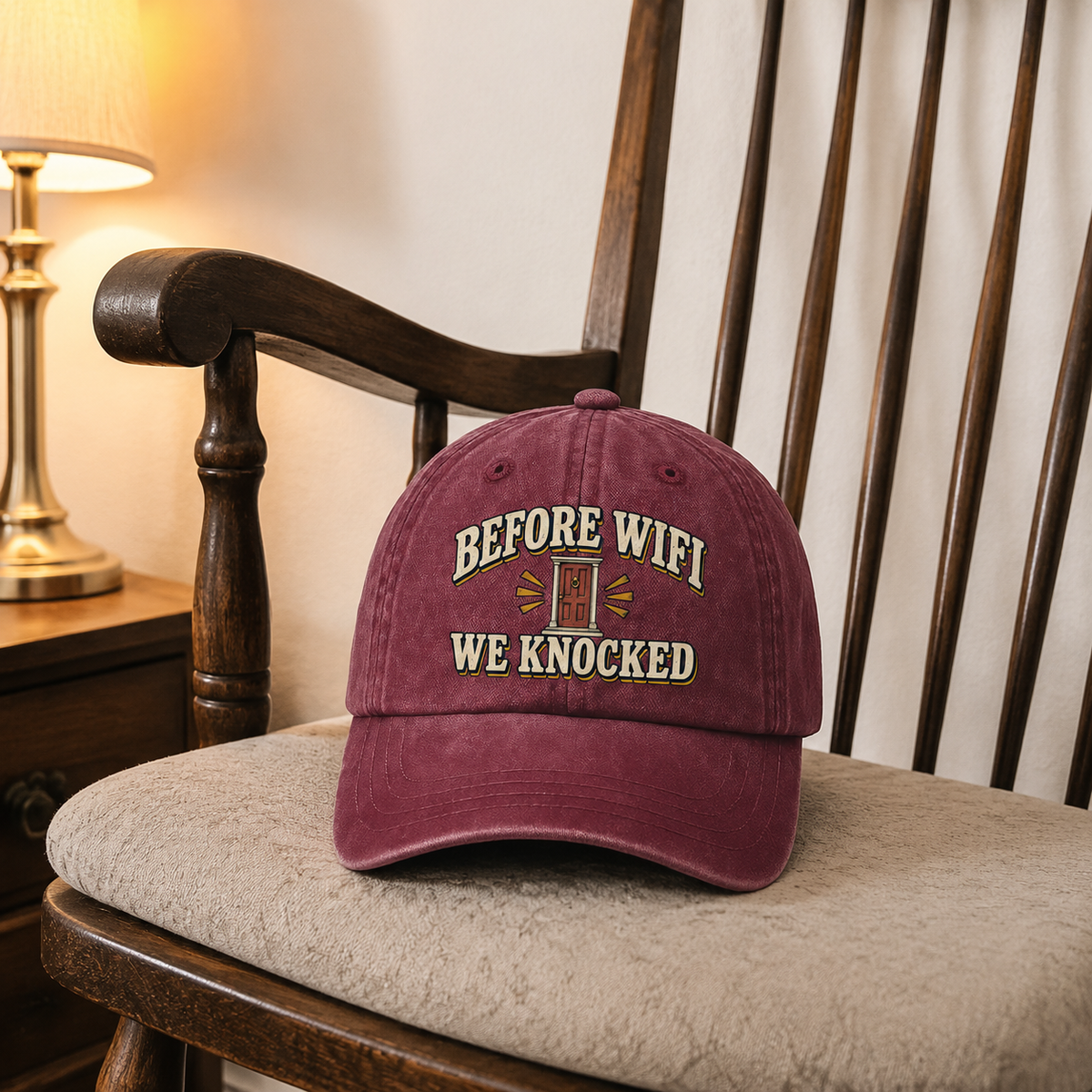 Burgundy vintage washed cap with printed “Before Wifi We Knocked” slogan displayed on chair.
