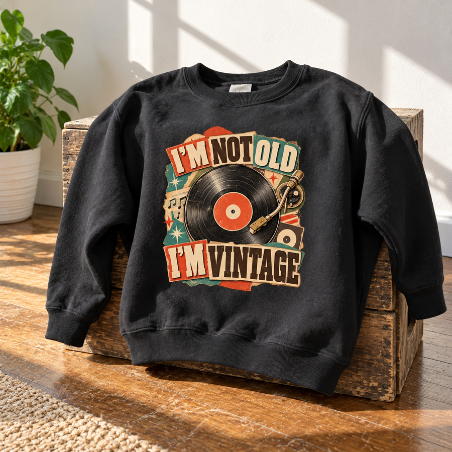 Black vintage sweatshirt with printed “I’m Not Old. I’m Vintage” record design on wooden crates