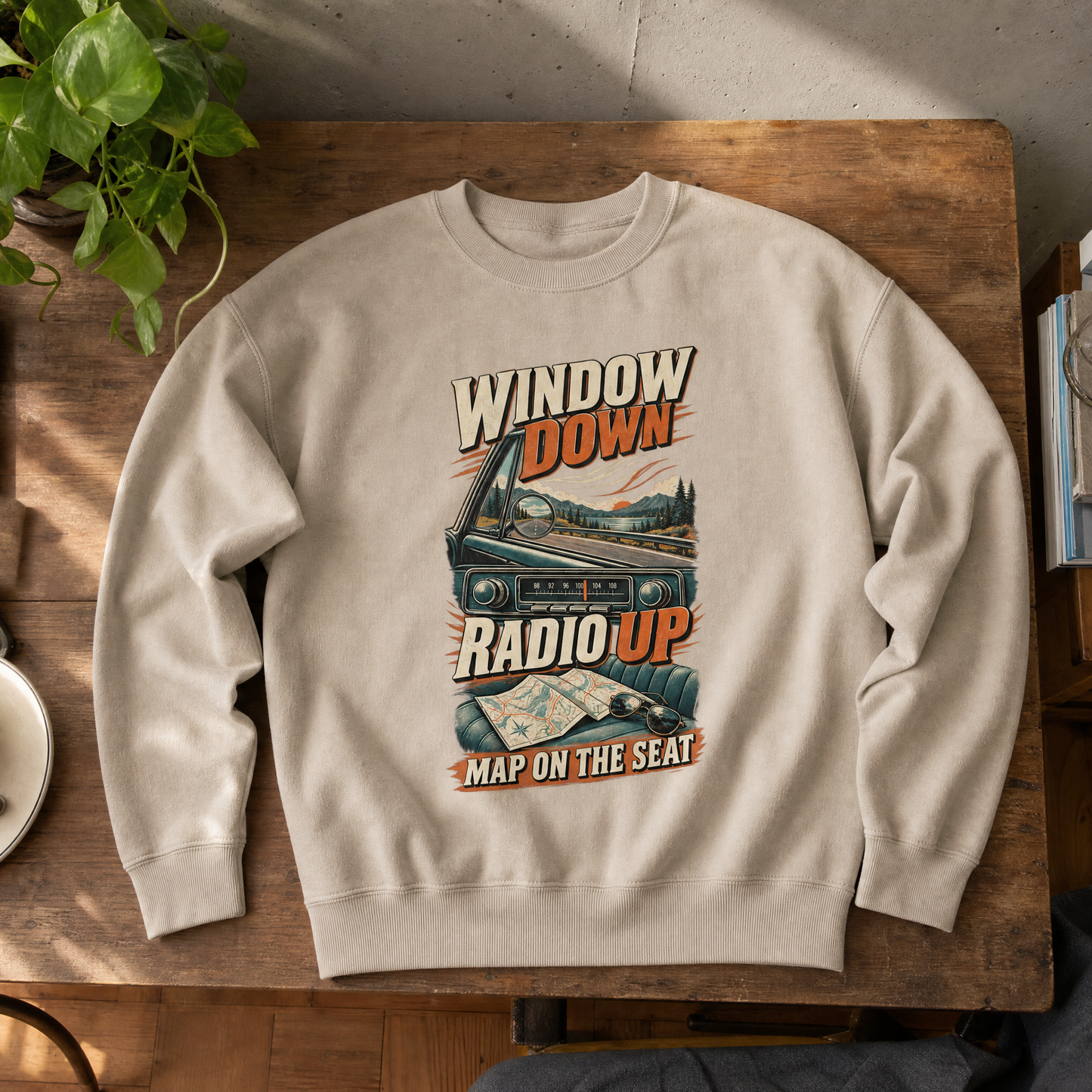 Beige vintage sweatshirt with printed “Window Down Radio Up” road trip design, top-down view