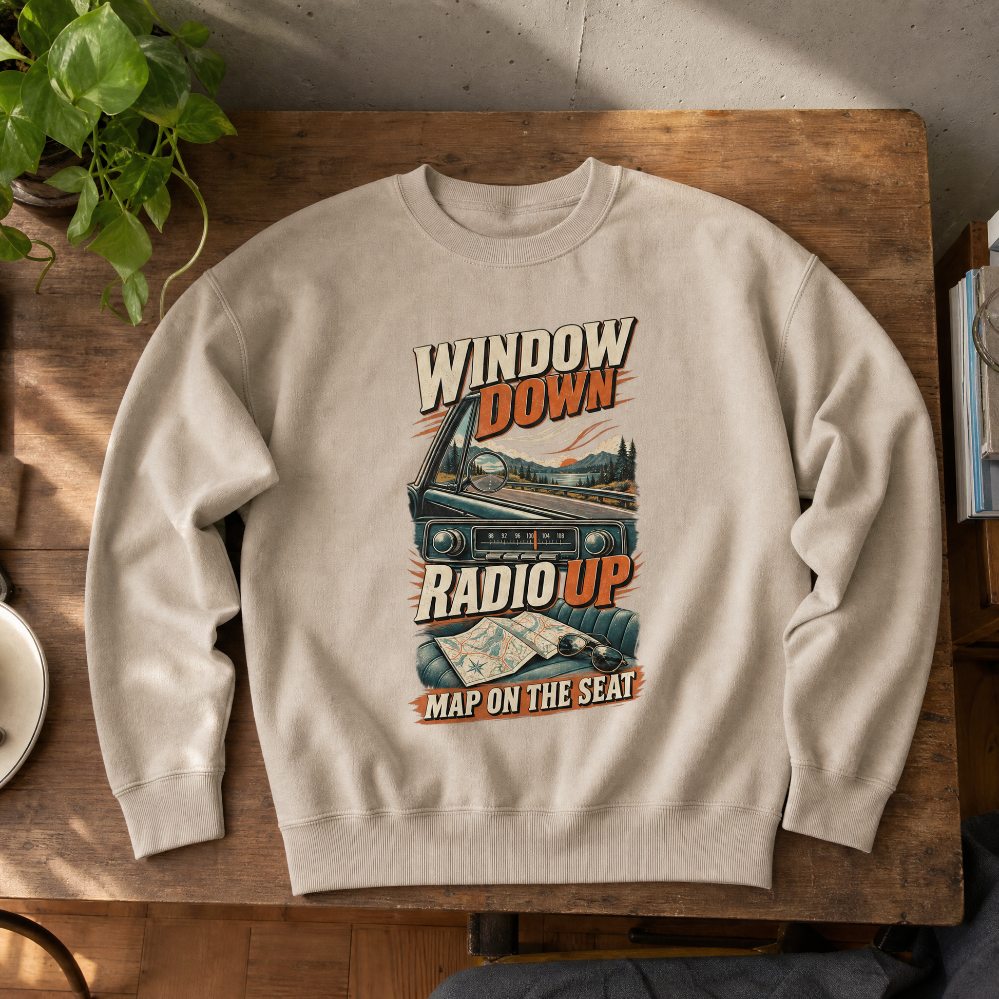 Beige vintage sweatshirt with printed “Window Down Radio Up” road trip design, top-down view