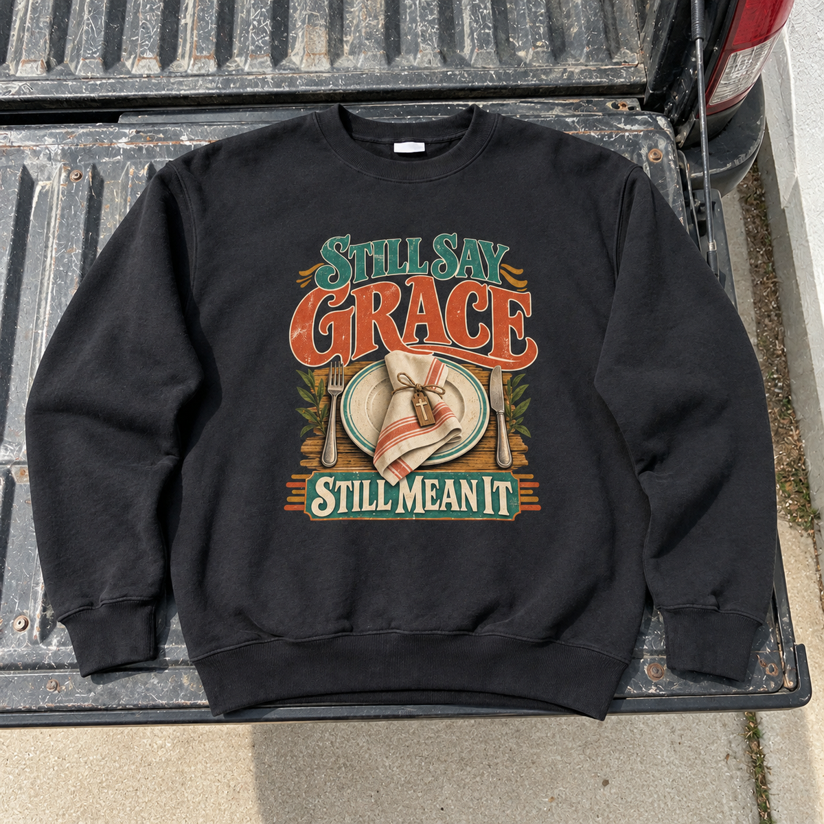 Black vintage sweatshirt with printed Still Say Grace Still Mean It design on tailgate