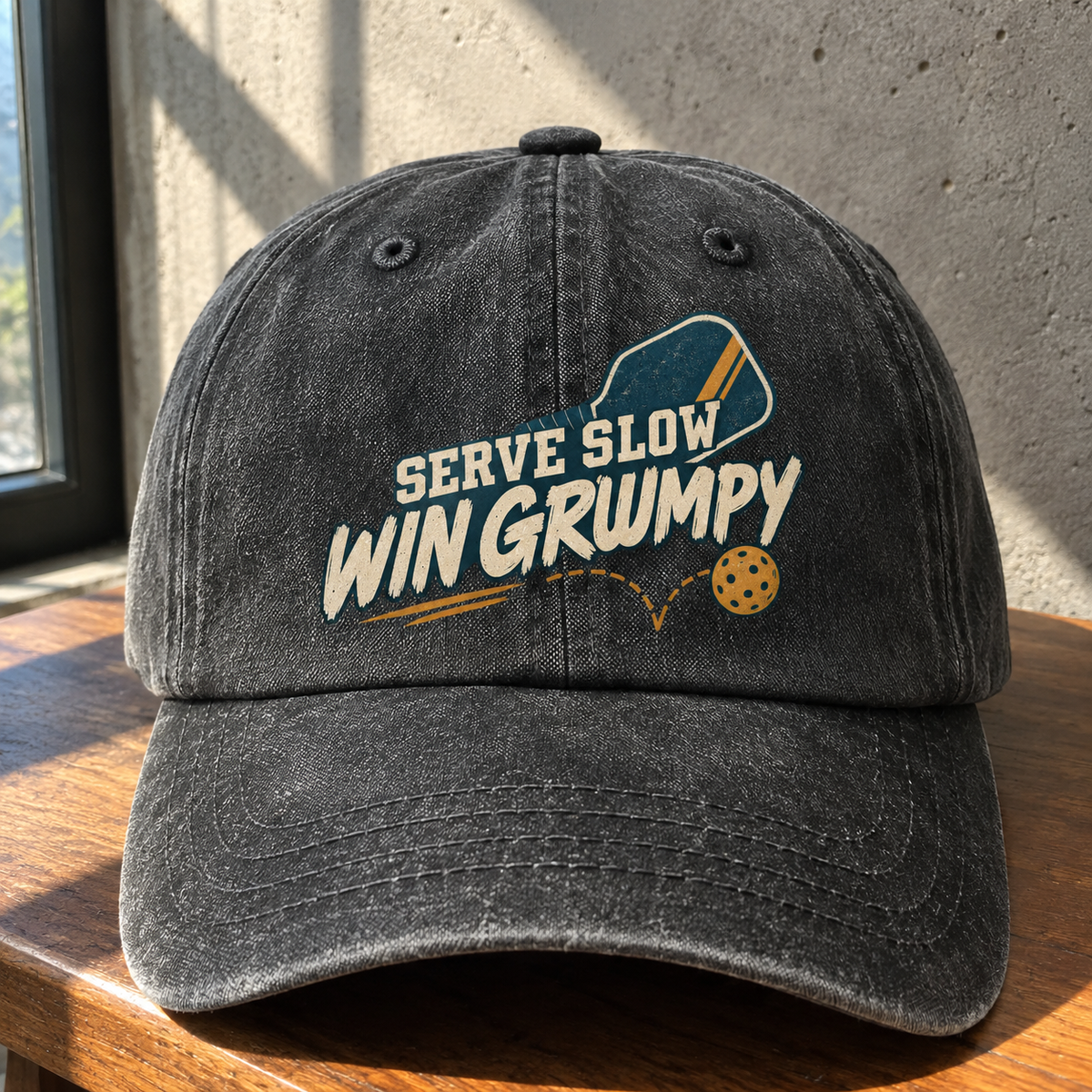Black vintage washed cap with printed Serve Slow Win Grumpy slogan, front hero view on wooden table