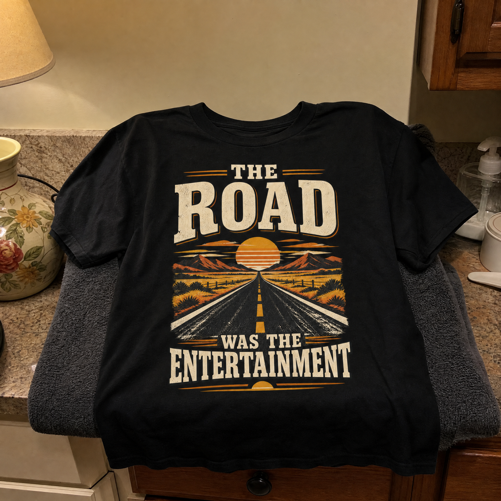 Black vintage t-shirt with printed “The Road Was The Entertainment” road and sunset design