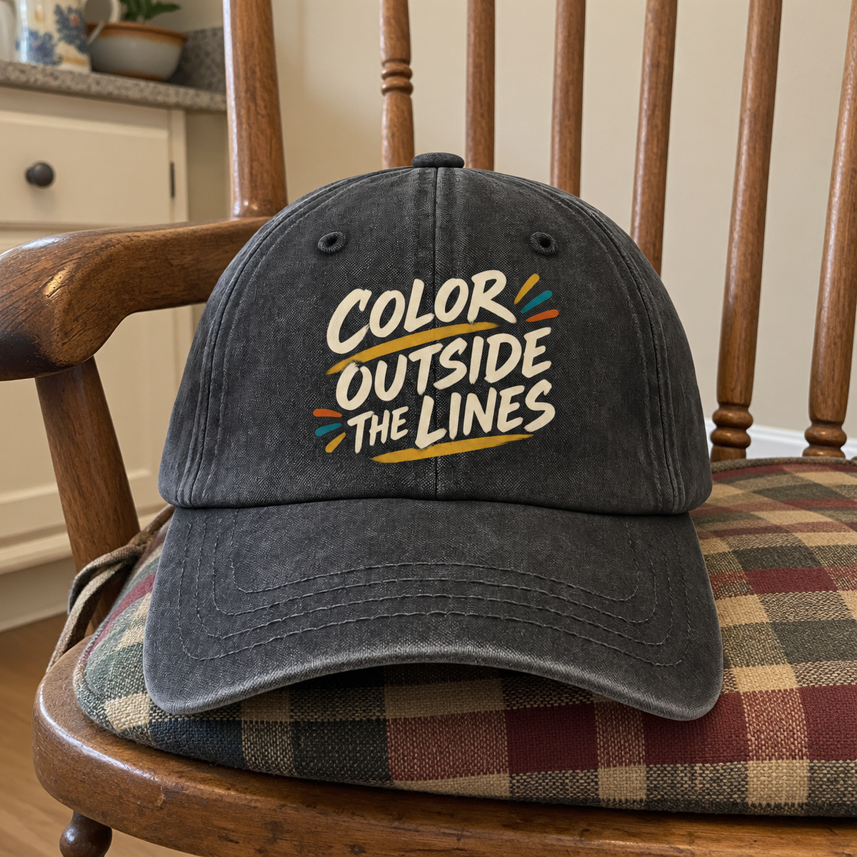 Black vintage washed cap with colorful printed Color Outside The Lines slogan, front view.