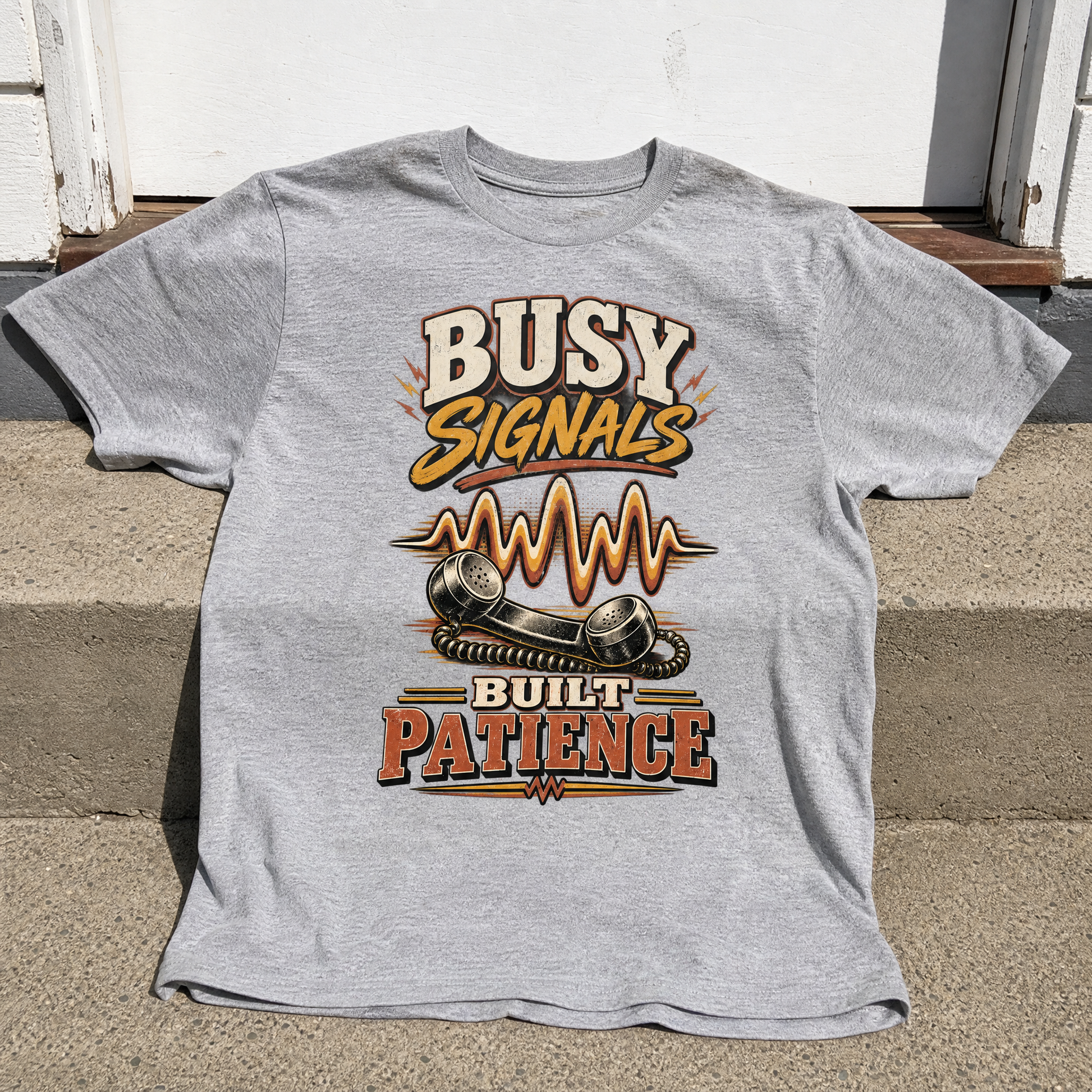 Gray vintage t-shirt featuring printed “Busy Signals Built Patience” telephone graphic, hero view.