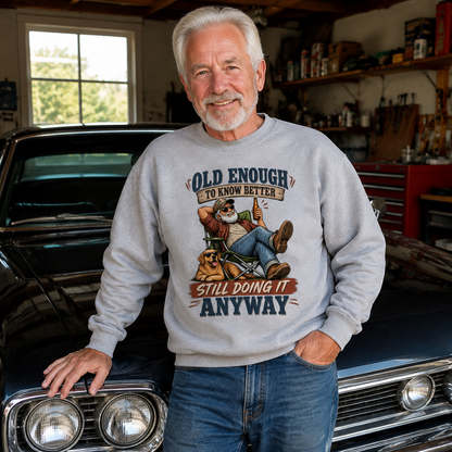 Senior man wearing gray vintage sweatshirt with printed Old Enough To Know Better slogan indoors