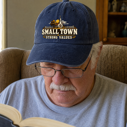 Navy vintage washed cap printed “Small Town Strong Values” worn by senior man reading