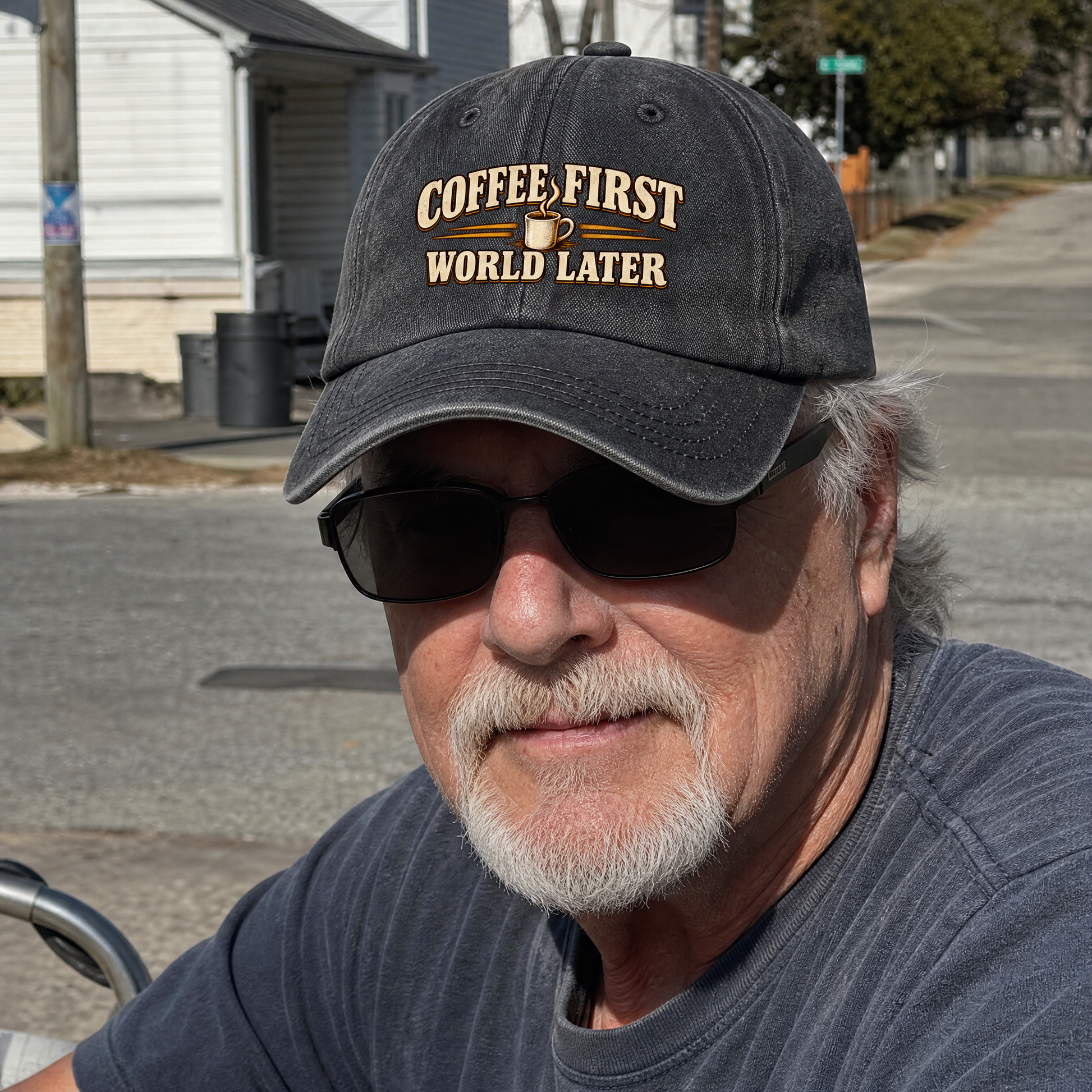 Black vintage washed cap featuring printed “Coffee First. World Later,” worn by senior man outdoors.