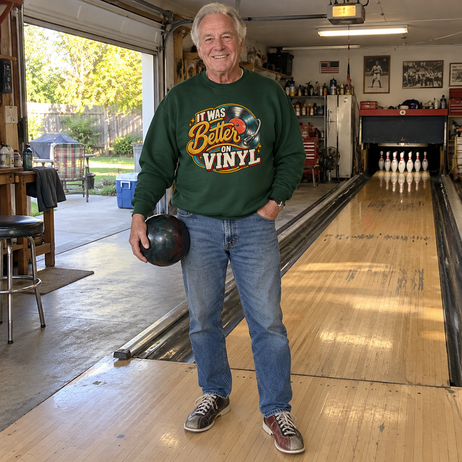 Senior man wears green vintage sweatshirt printed It Was Better On Vinyl beside bowling lane