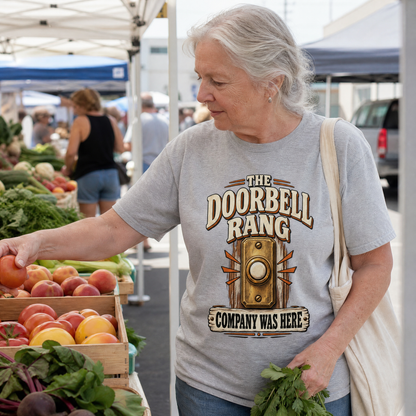 Senior woman wearing gray vintage t-shirt with printed Doorbell Rang design at farmers market.