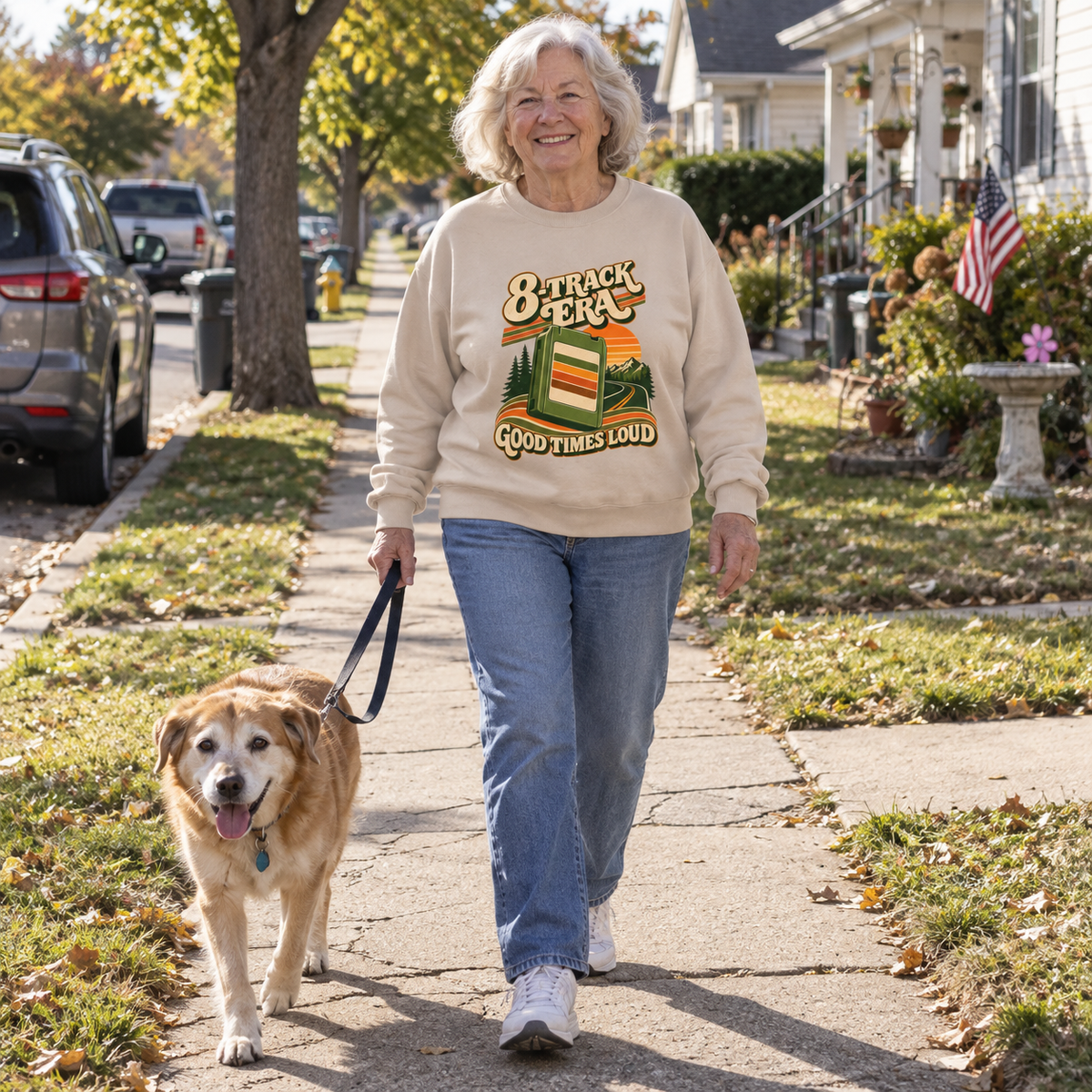 Senior woman walks dog wearing beige vintage sweatshirt printed 8-Track Era Good Times Loud