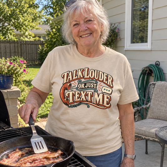 Senior woman grilling outdoors in beige vintage t-shirt with printed Talk Louder Or Just Text Me slogan
