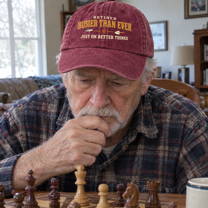 Vintage washed cap with printed Retired Busier Than Ever slogan on senior man playing chess indoors