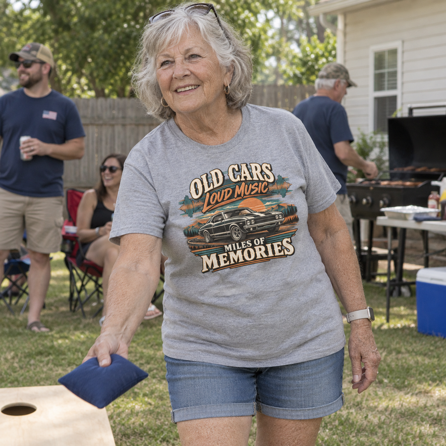 Senior woman playing cornhole wears gray vintage t-shirt with printed car and slogan.