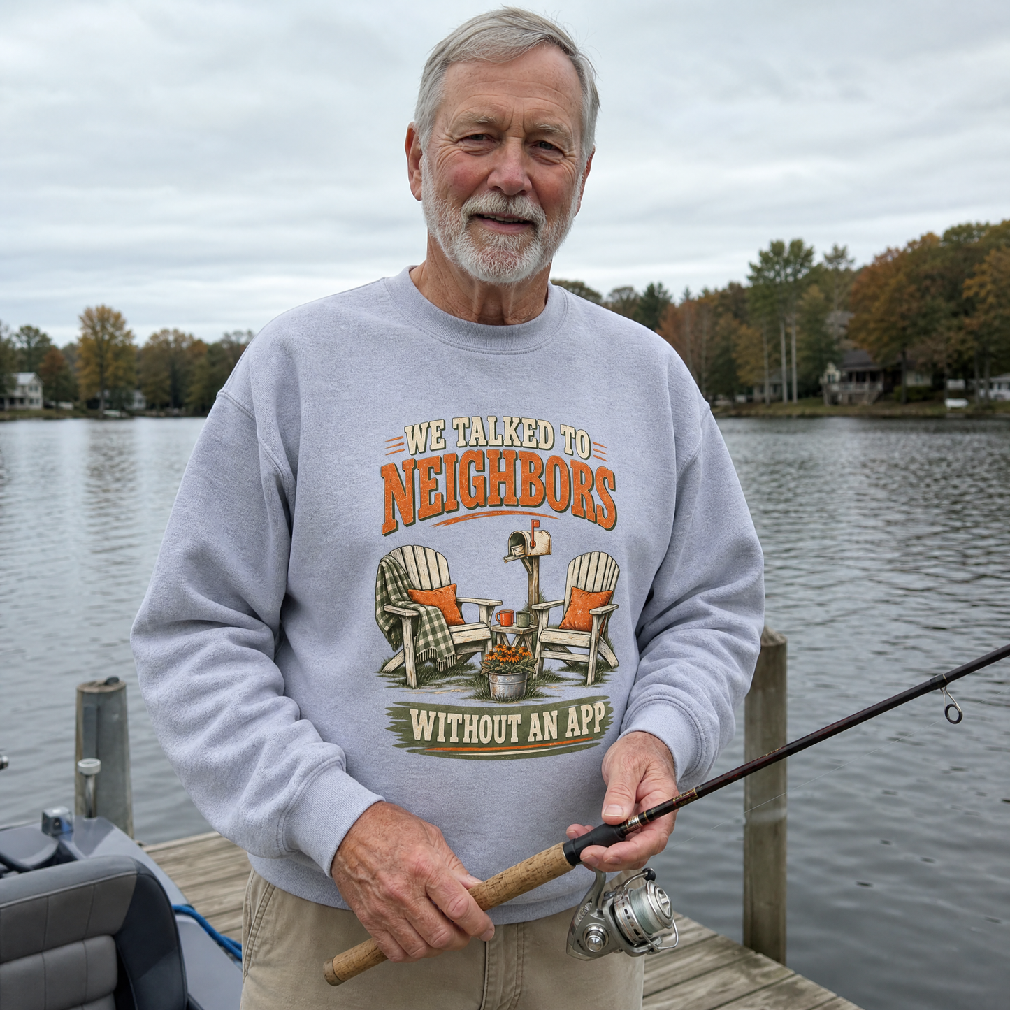 Senior man wearing gray vintage sweatshirt with printed neighbor slogan, fishing by a lake.